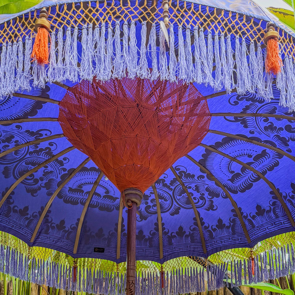 Decorative umbrella with blue canopy and red center, surrounded by green foliage