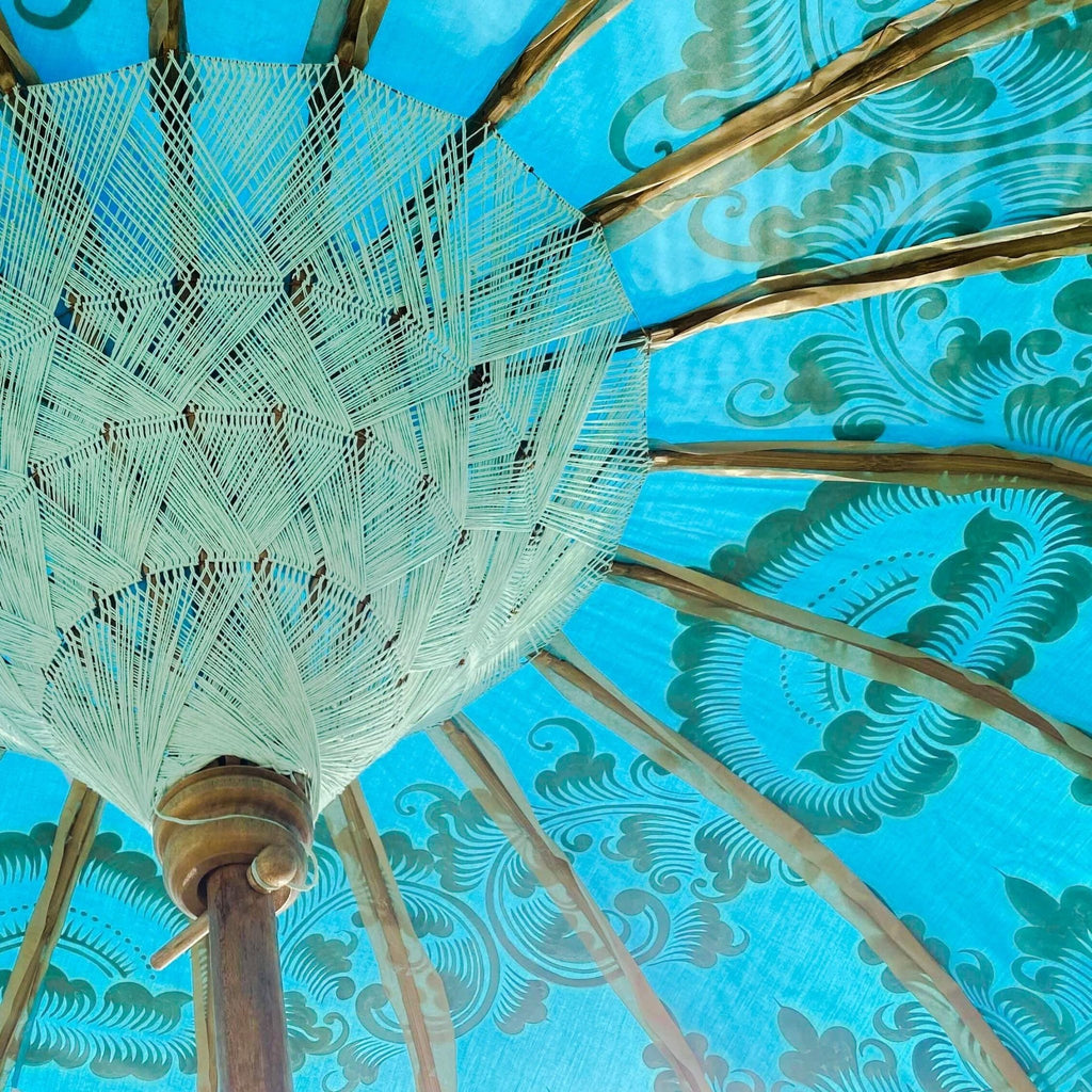 Interior view of the Big Jack Parasol showcasing white threading, bamboo structure, and turquoise fabric with gold patterns.