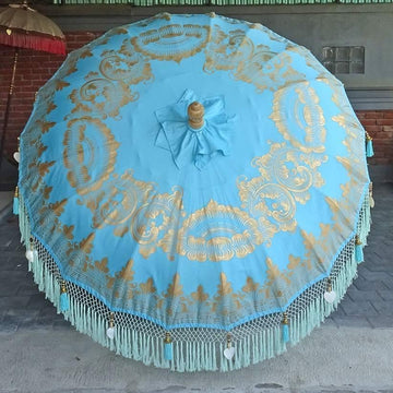 Transform your outdoor space with the Big Jack Parasol. Bold turquoise canvas with gold hand-painted details, handcrafted durian wood pole, and elegant tassels.