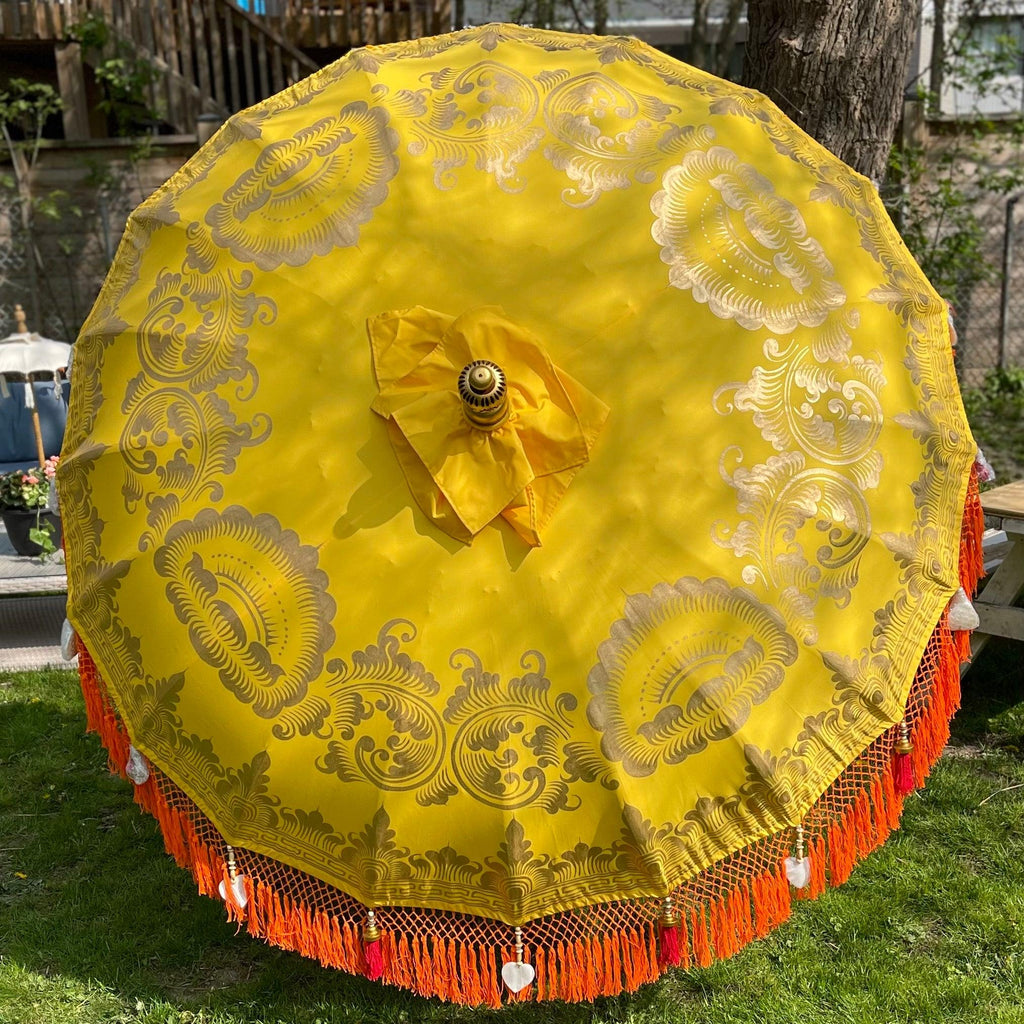 Arabella Parasol in vibrant yellow with gold hand-painted details and orange fringes, perfect for elegant outdoor spaces.