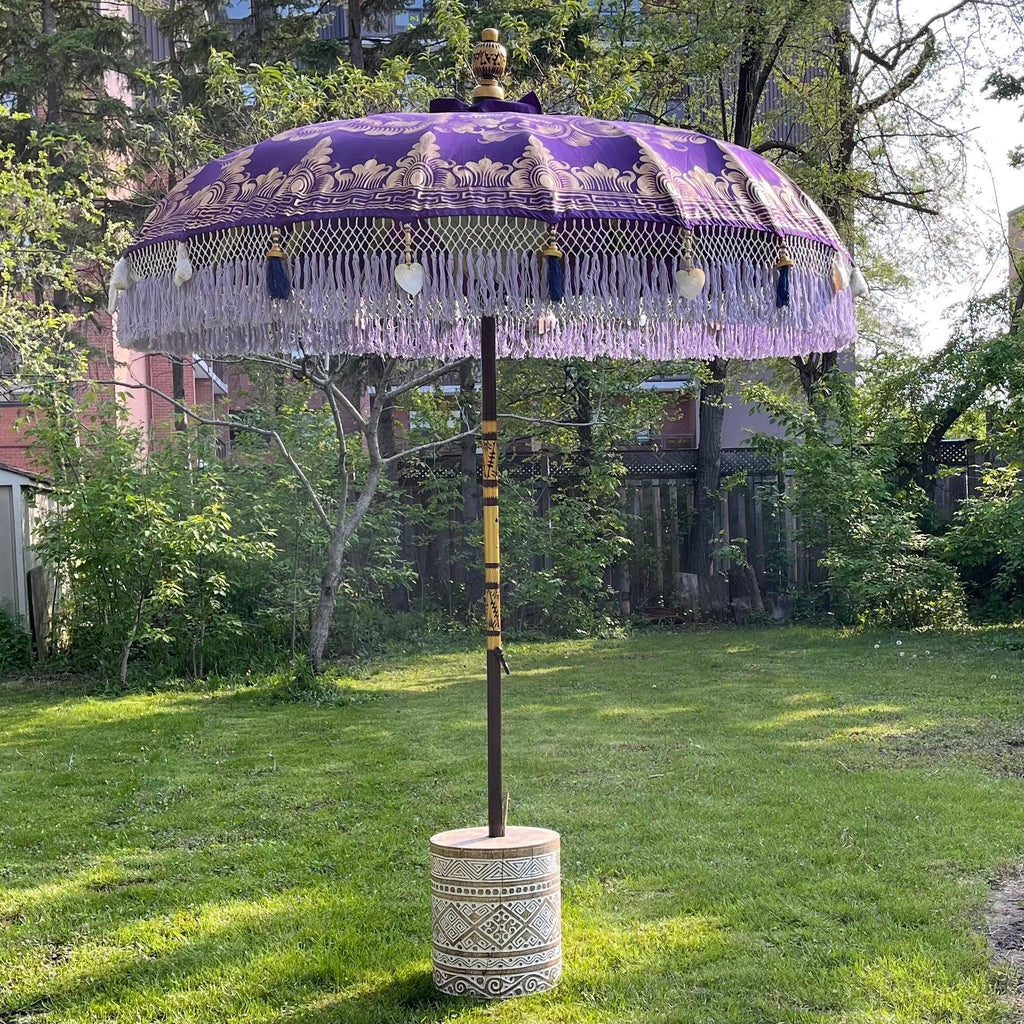 Claudia Parasol standing on a decorative base, blending elegance with outdoor charm.