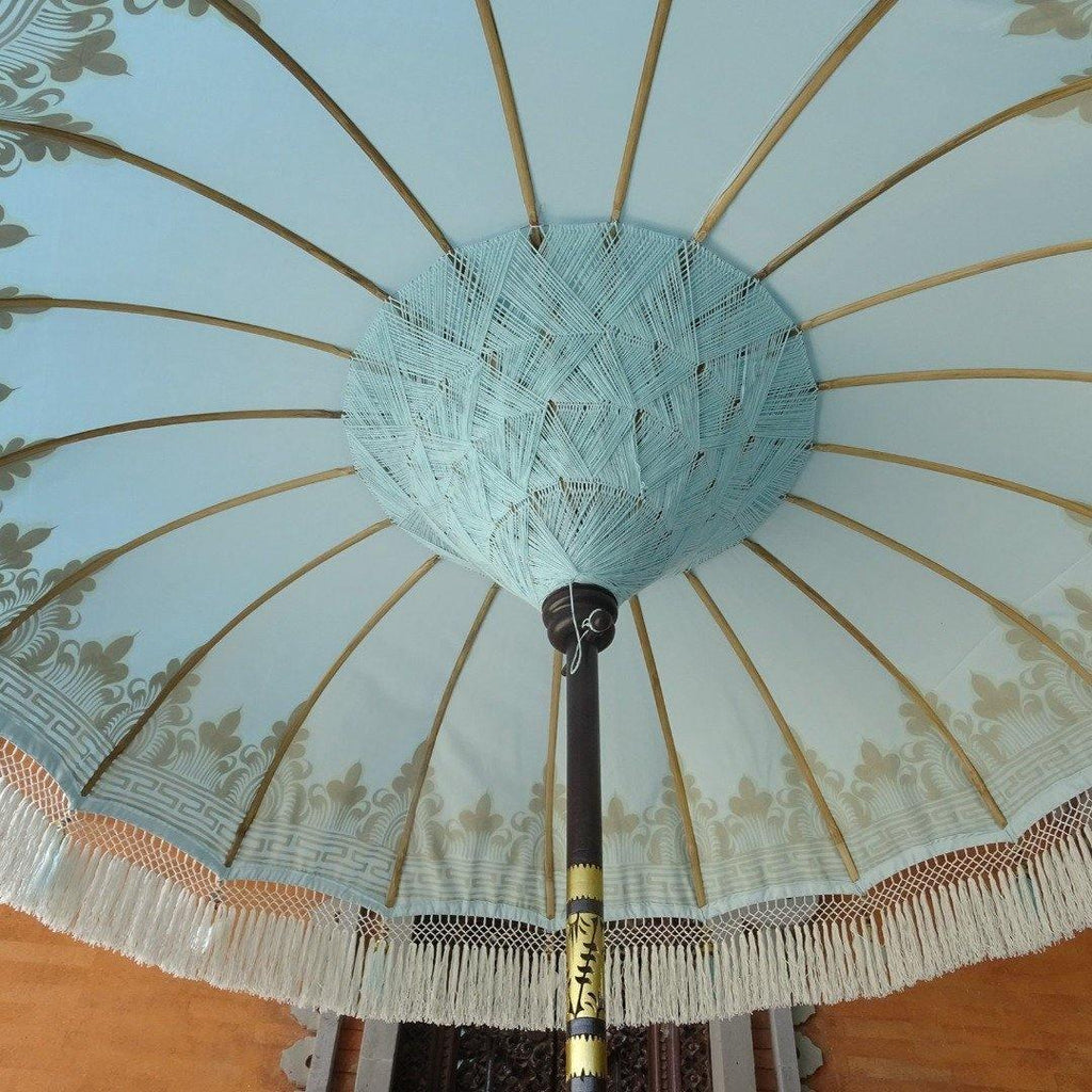 Detailed silver artwork on the Baby Blue Parasol, featuring handcrafted wooden elements and delicate blue tassels.