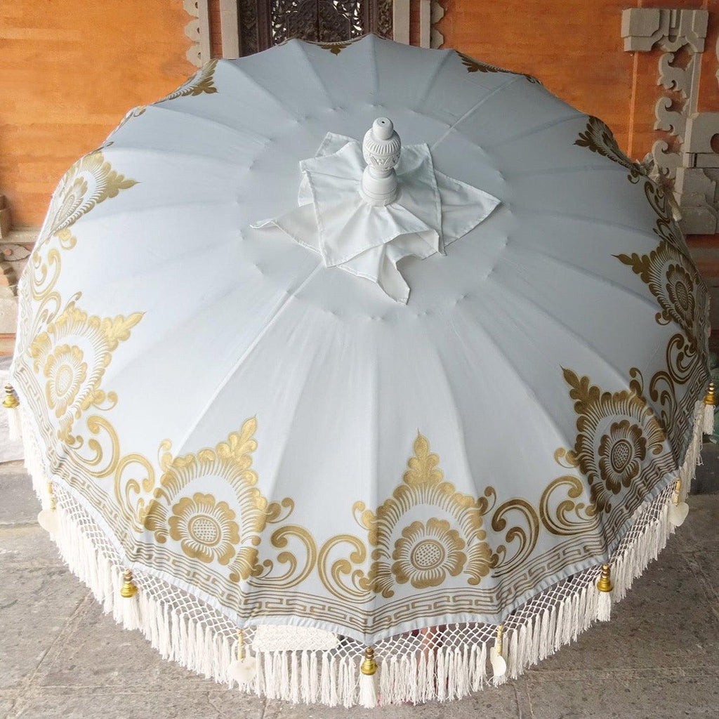 Ally Parasol in white and gold with handcrafted details and elegant fringes for luxurious outdoor settings.